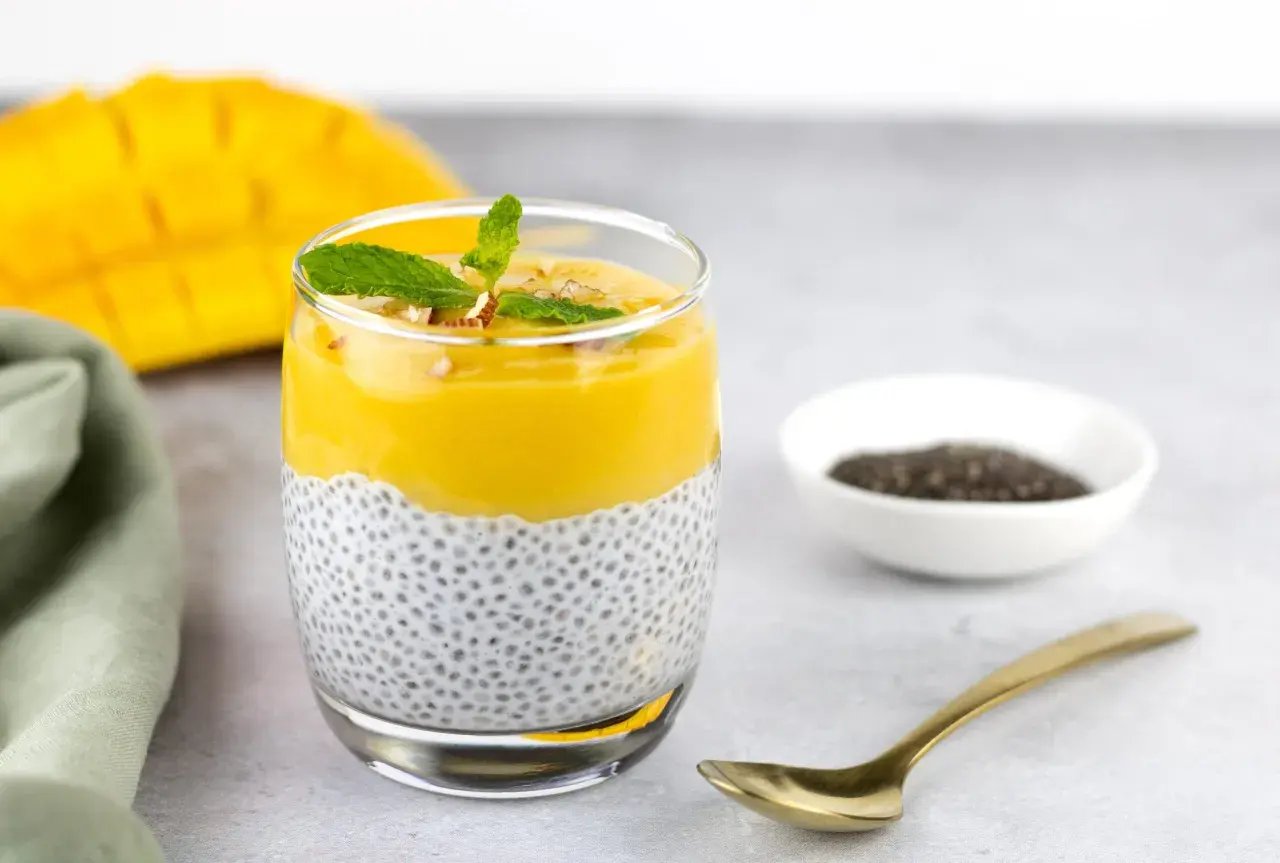 Un délicieux dessert graines de chia avec une couche crémeuse de mangue, garni de menthe et de noix.